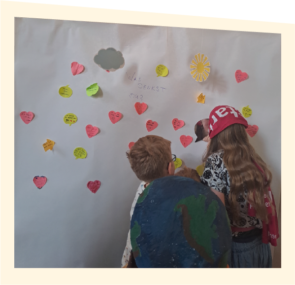 zwei Kinder, die Zettel mit Ideen an eine Wand kleben